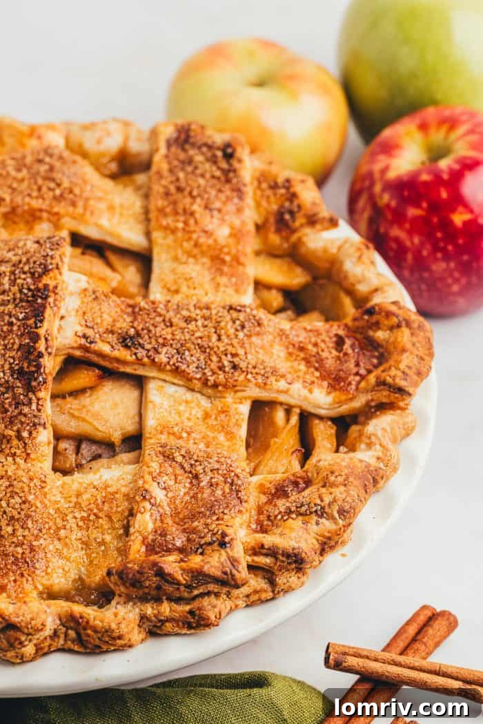 A tantalizing side view of a golden-brown caramel apple pie, showcasing its thick, inviting filling and perfectly crimped cheddar crust.