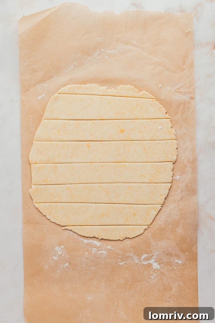 A rolled-out pie dough is neatly cut into even strips, ready to be woven into a beautiful lattice topping for the pie.