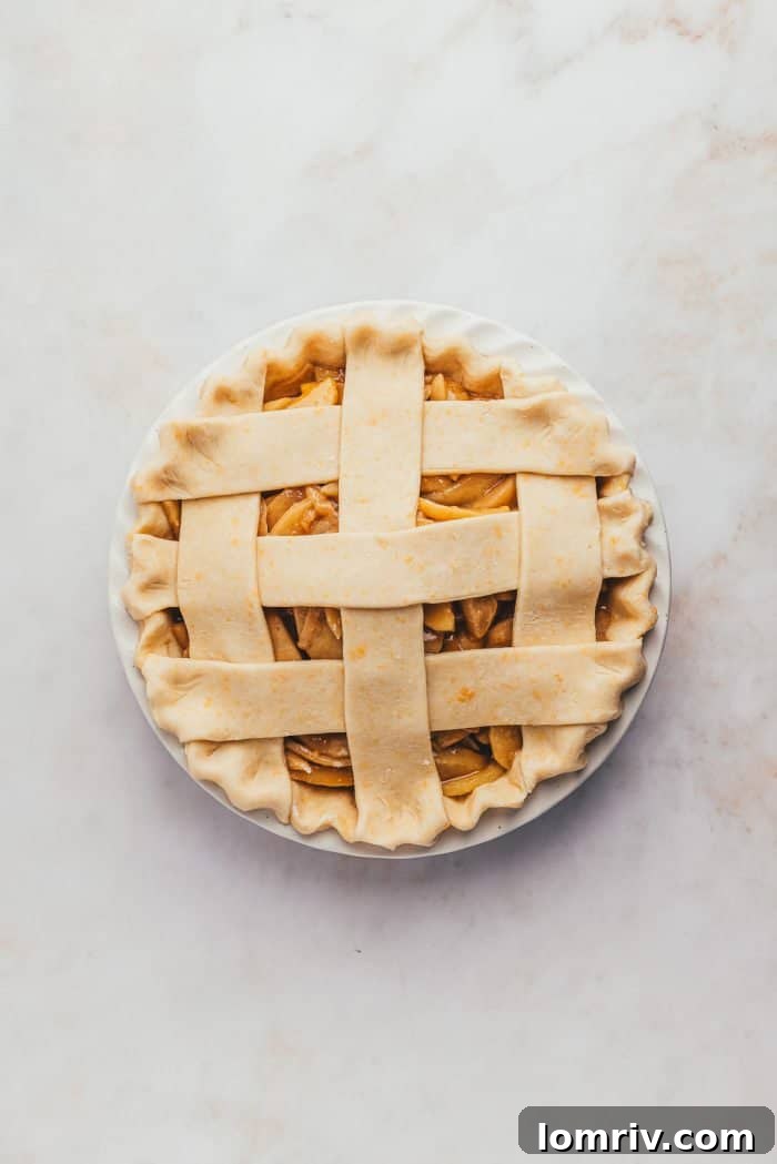 A beautifully assembled unbaked apple pie featuring an intricate lattice crust, ready for its golden transformation in the oven.