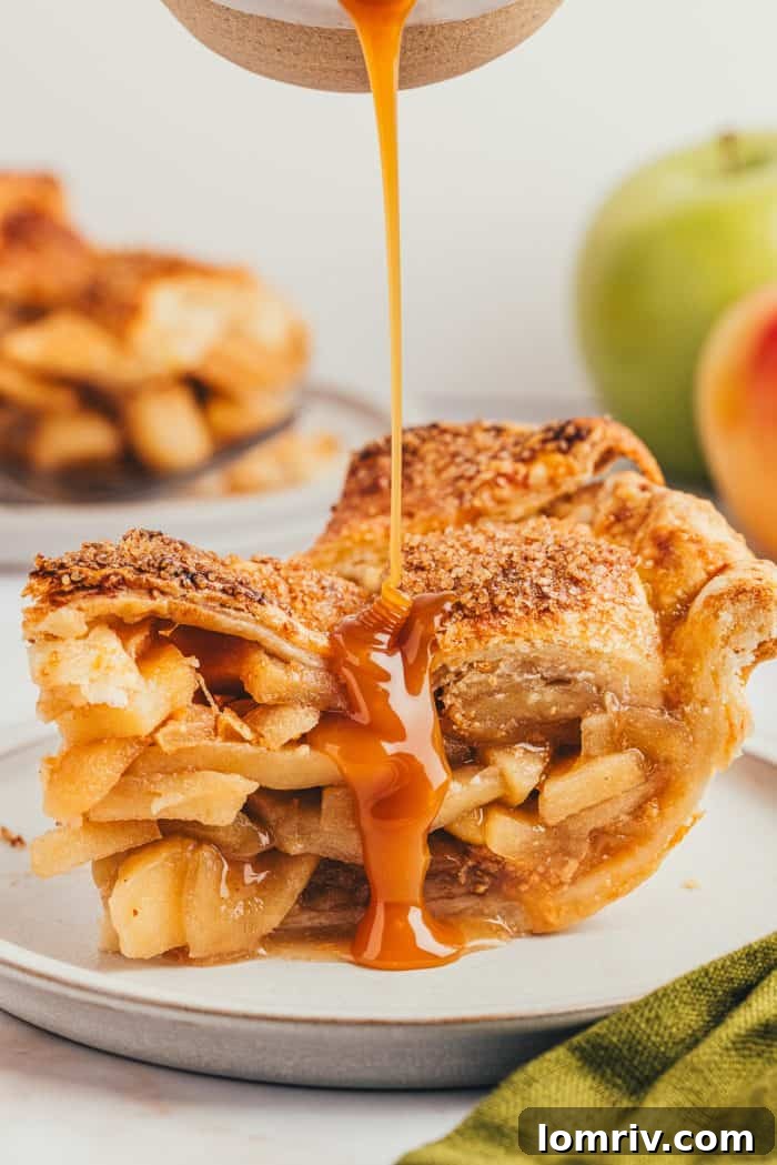 Decadent caramel sauce being generously poured over a delectable slice of apple pie on a white plate, highlighting its tempting richness.