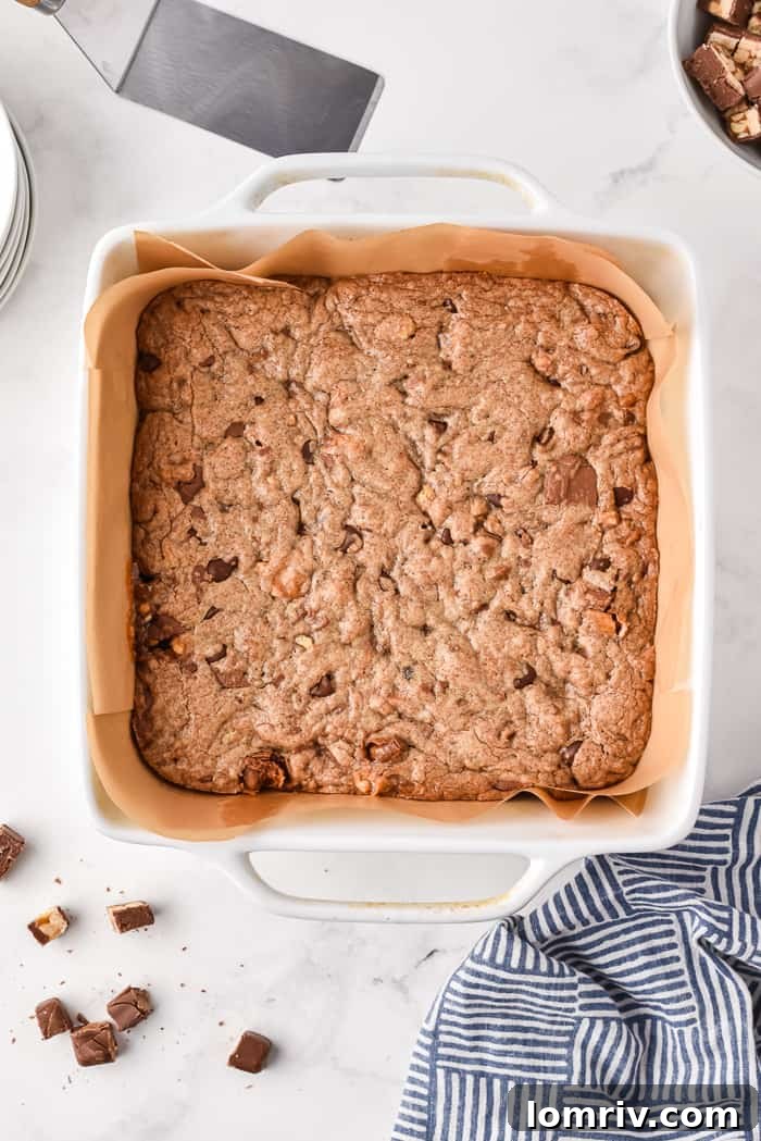 Hand reaching for a Chocolate Bar Cookie Bar with melted chocolate