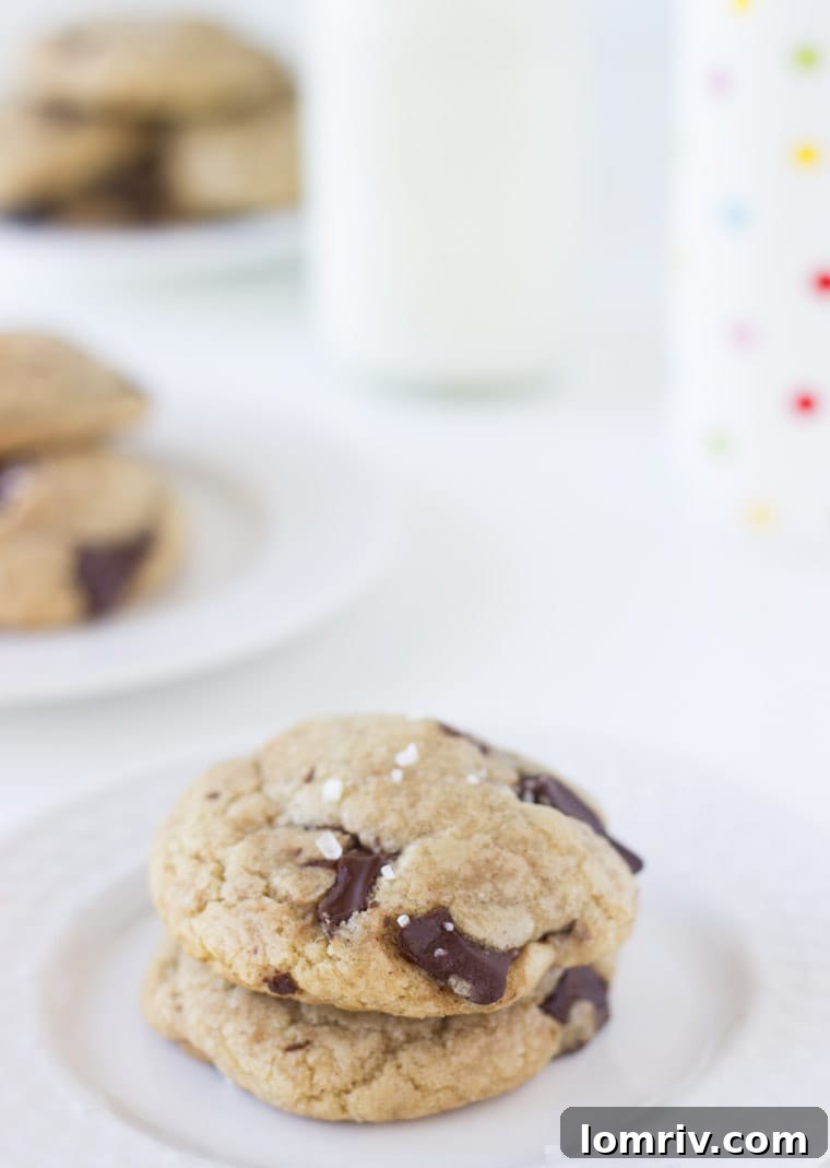 A plate of fresh-baked dairy-free coconut chocolate chunk cookies, garnished with coarse sea salt.