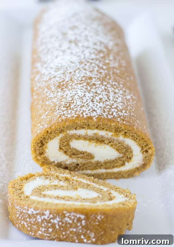 A beautifully sliced classic pumpkin roll cake with a generous swirl of spiced ginger cream cheese frosting, perfectly garnished for autumn celebrations.
