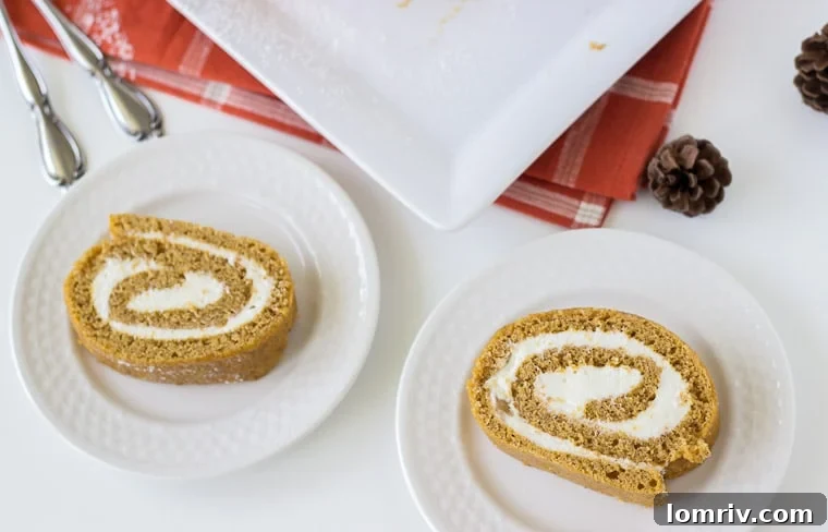 A close-up view of a fresh pumpkin roll cake with ginger buttercream, sliced and ready for serving, showcasing the perfect spiral.