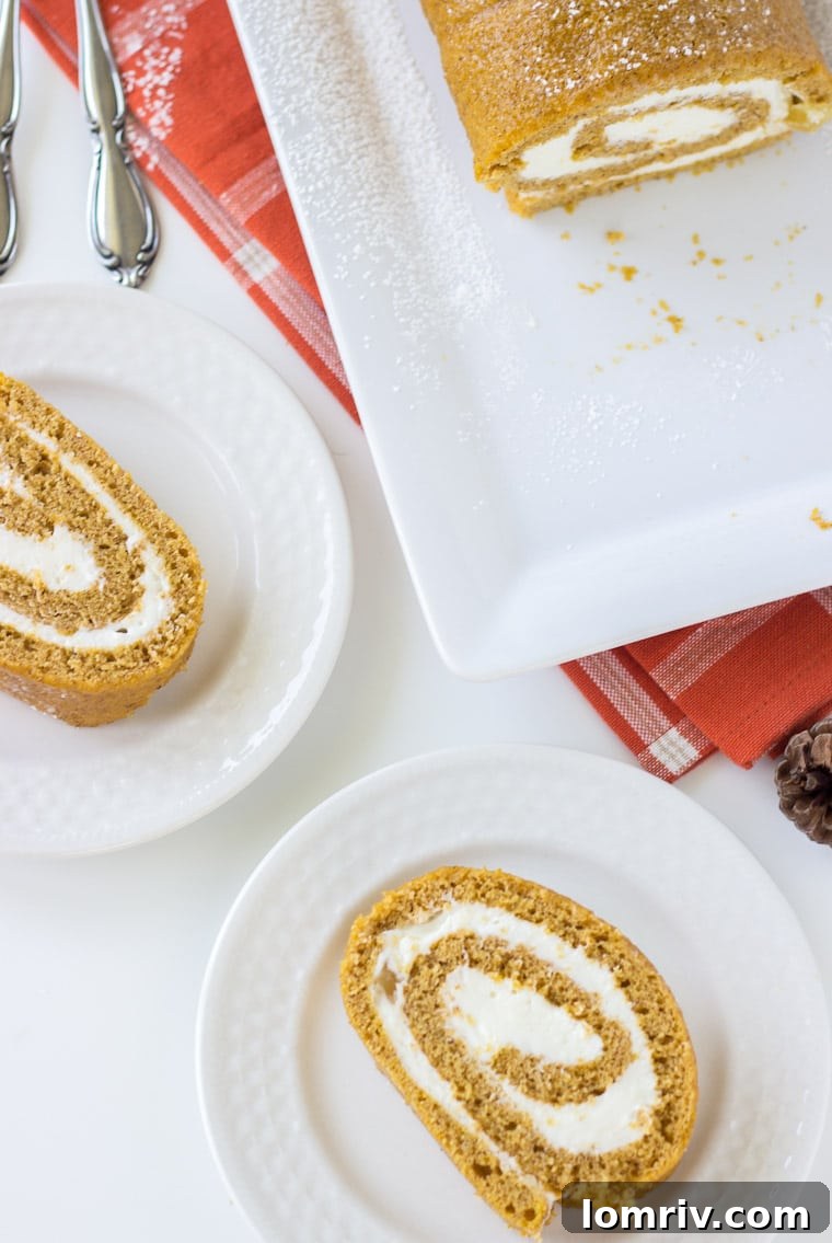Close-up of a pumpkin roll cake slice, showing the moist cake and creamy ginger frosting spiral, placed on an autumn-themed background.