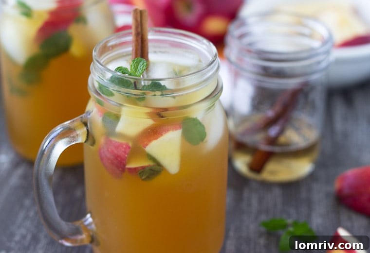 Close-up shot of an Apple Cider Mojito, showcasing the mint leaves, apple chunks, and the rich color of the drink.