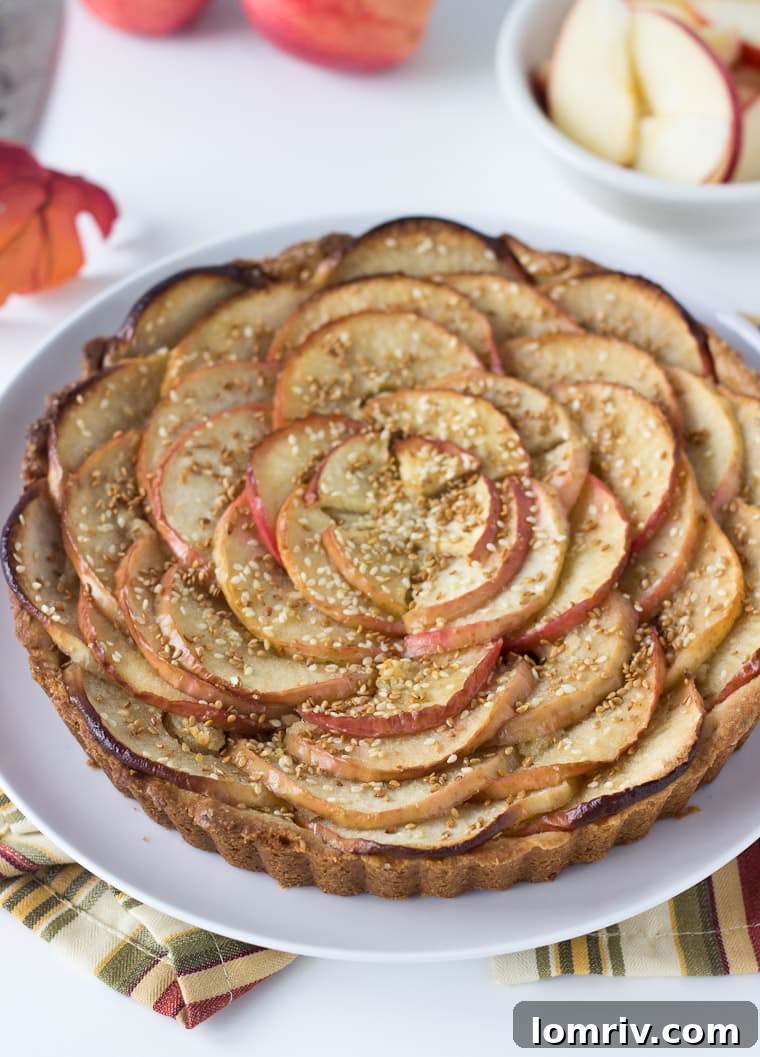 A beautifully baked apple tart showcasing a golden crust, caramelized apples, and a generous sprinkle of toasted sesame seeds, ready to be served.