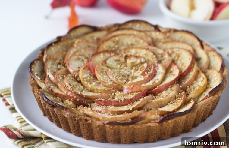 Close-up of a rustic apple tart adorned with toasted sesame seeds, highlighting the golden-brown crust and perfectly arranged apple slices.