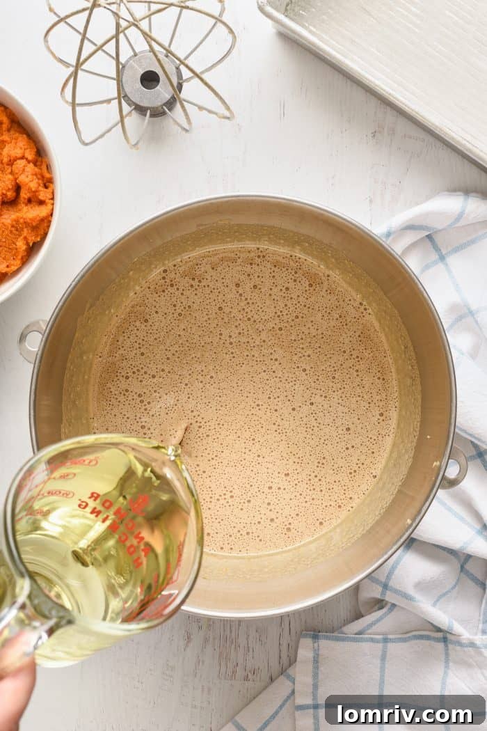 Adding vegetable oil to the batter in a stand mixer.