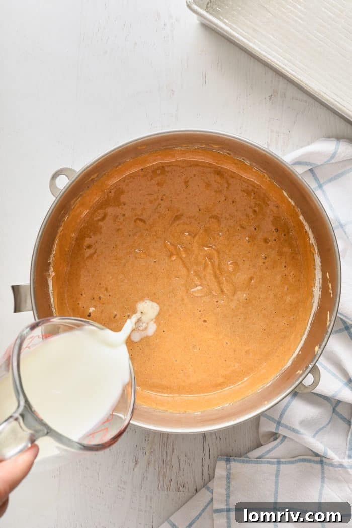 Adding milk to the batter in stages.