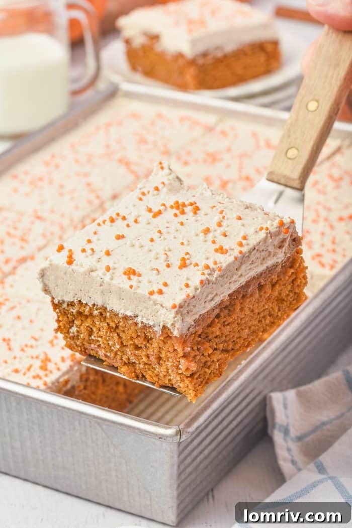 A slice of pumpkin cake being carefully removed from the cake pan, revealing the moist interior.