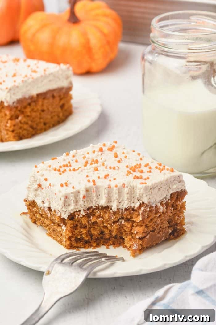A pumpkin cake bar with a bite taken out of it, showing the soft cake and thick frosting.