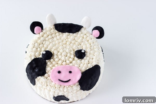 Detailed view of the easy and adorable fondant and frosting decorated cow cake, ideal for farm-themed parties. Learn how to make this delightful creation on BlahnikBaker.com.