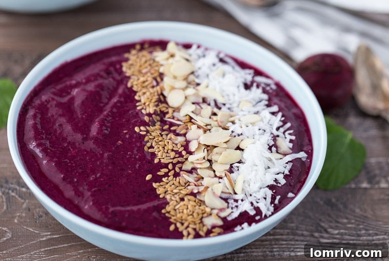 Close-up of a Berry Beets Smoothie Bowl with a spoon, highlighting its creamy texture and fresh toppings.