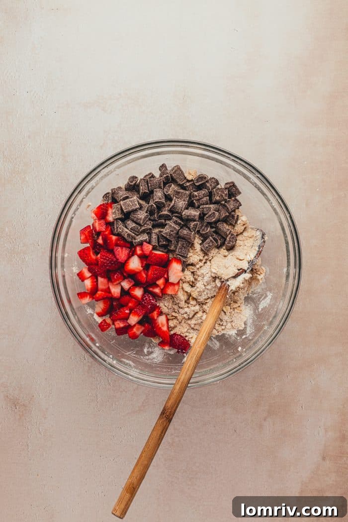 A glass bowl with the dry ingredients and chopped strawberries and chocolate.