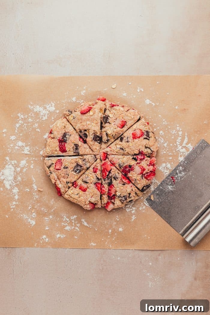 The scone dough on parchment paper shaped into a circle and sliced into scones.