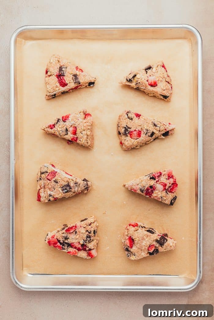 The unbaked scones on parchment paper on a baking sheet. 