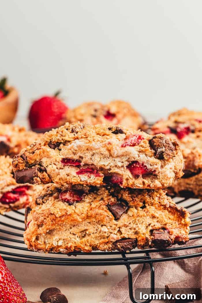 Two strawberry chocolate scones stacked on each other on a cooling rack.
