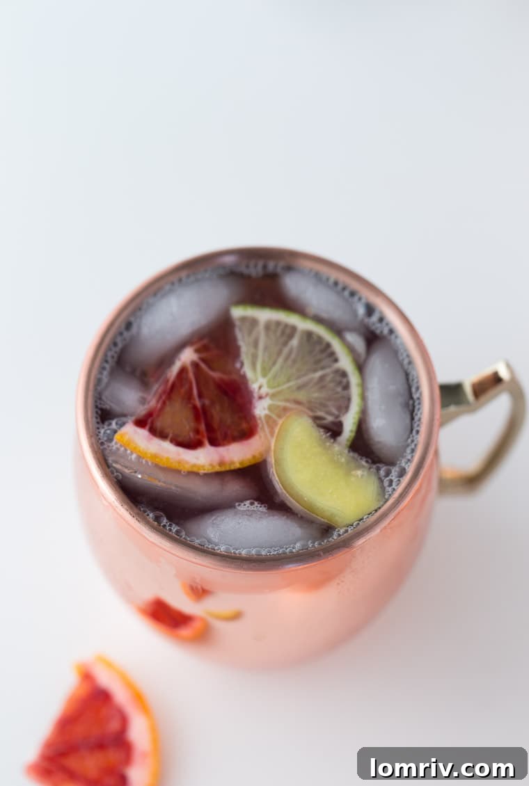 A vibrant Blood Orange Moscow Mule served in a classic copper mug, garnished with a blood orange slice and fresh mint, emphasizing its refreshing appeal.