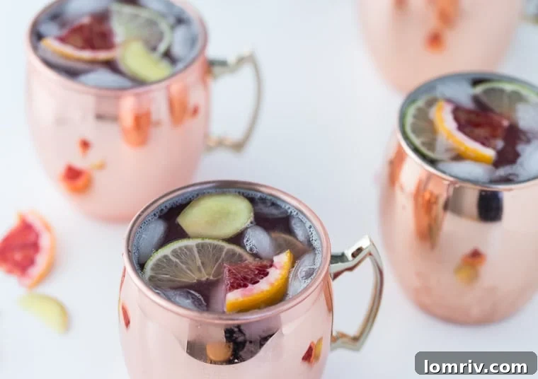 Close-up of a Blood Orange Moscow Mule in a frosty copper mug, showing the condensation and the inviting color of the drink.