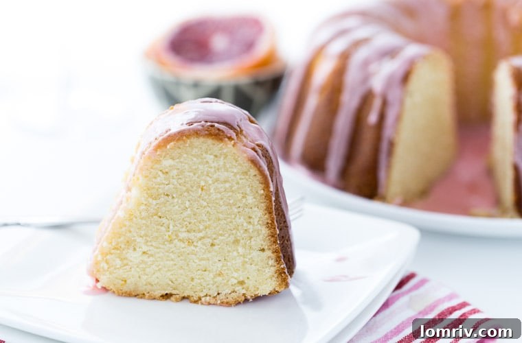 Close-up of the beautiful pink glaze on a Blood Orange Mimosa Cake, highlighting its moist texture and vibrant color.
