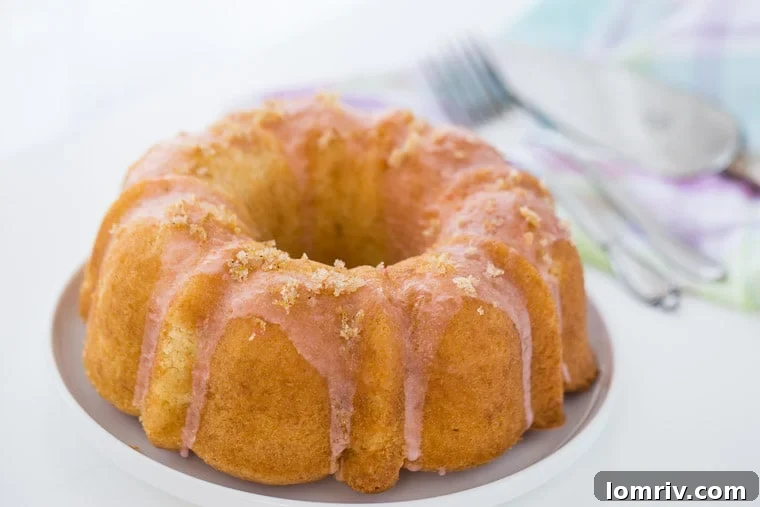 A close-up of a slice of grapefruit vanilla bean pound cake, showing the moist crumb and glistening glaze.