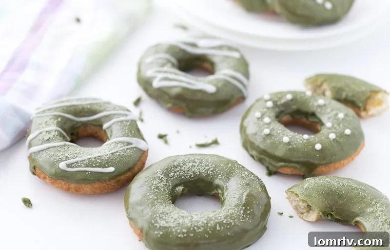 Freshly glazed coconut matcha donuts arranged on a wire rack, ready to be enjoyed.