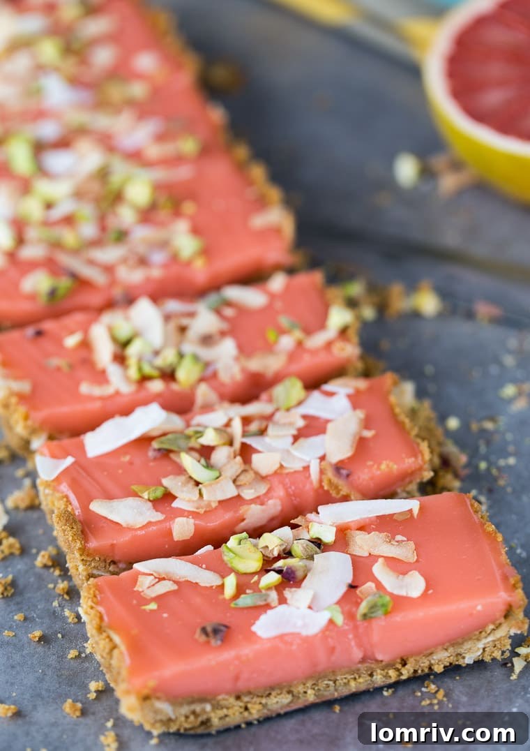 A serving of grapefruit tart, highlighting the vibrant curd and the thick, textured coconut graham cracker crust.