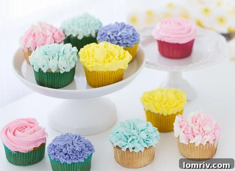 A baker's hands expertly coloring vanilla buttercream frosting with gel paste food colors in preparation for decorating flower cupcakes.