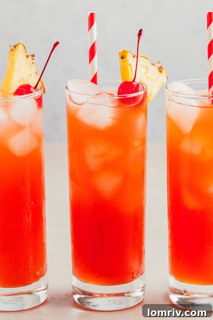 Three glasses filled with Planter's Punch and decorated with maraschino cherries and slices of pineapple.