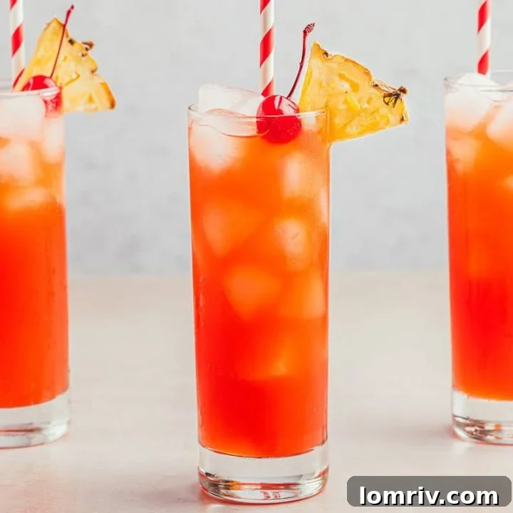 Three glasses filled with Planter's Punch and decorated with maraschino cherries and slices of pineapple.