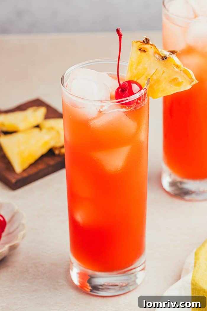 Two glasses filled with Planter's Punch and decorated with maraschino cherries and slices of pineapple.