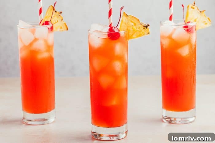 Three glasses filled with Planter's Punch and decorated with maraschino cherries and slices of pineapple.