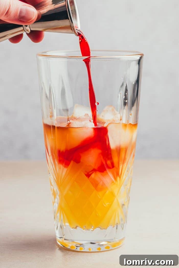 Grenadine syrup being poured into a glass.