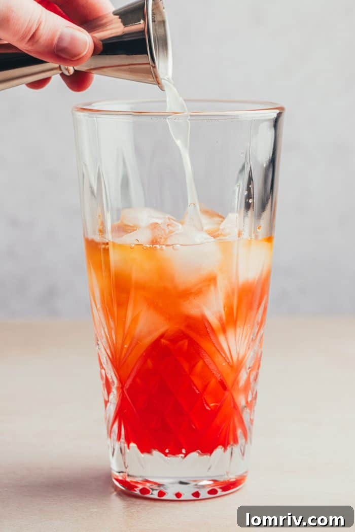Lemon juice being poured into a glass with the ingredients for Planter's Punch.