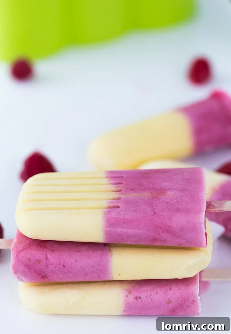Naturally sweetened, creamy raspberry mango yogurt pops with vibrant fruit layers, perfect for a healthy summer treat.