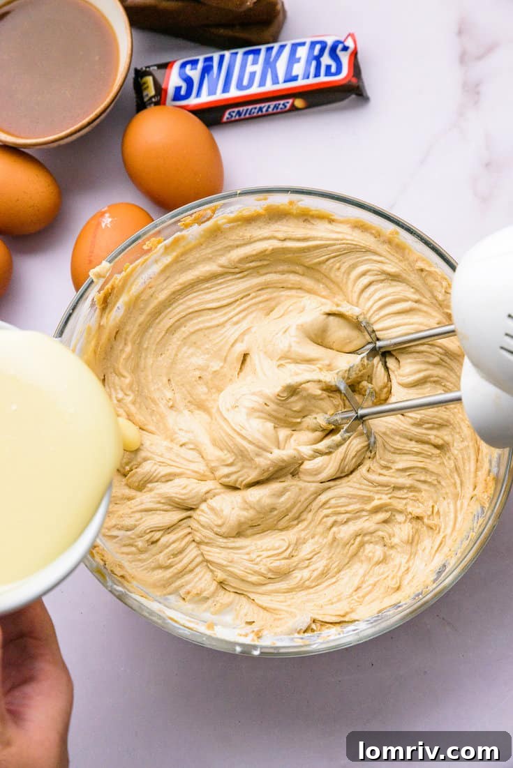 Sweetened condensed milk being added to peanut butter cheesecake filling