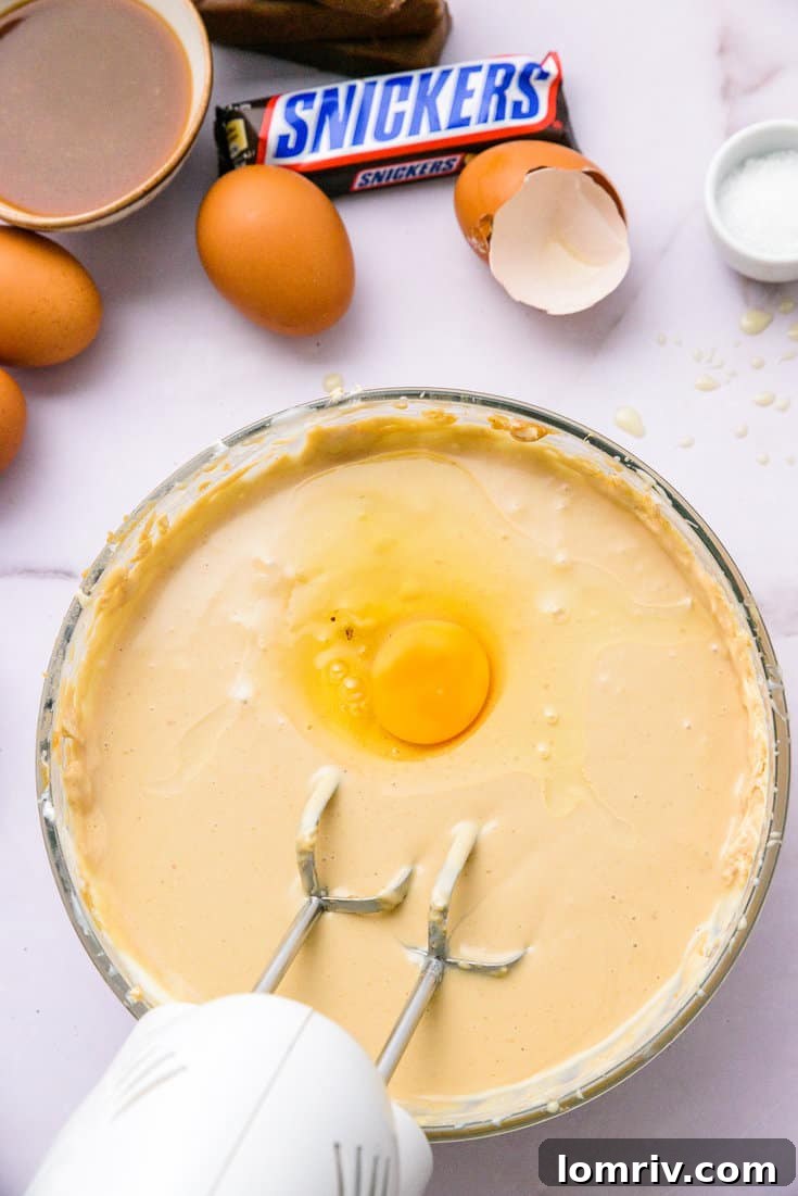 Eggs, vanilla, and salt being mixed into the cheesecake filling