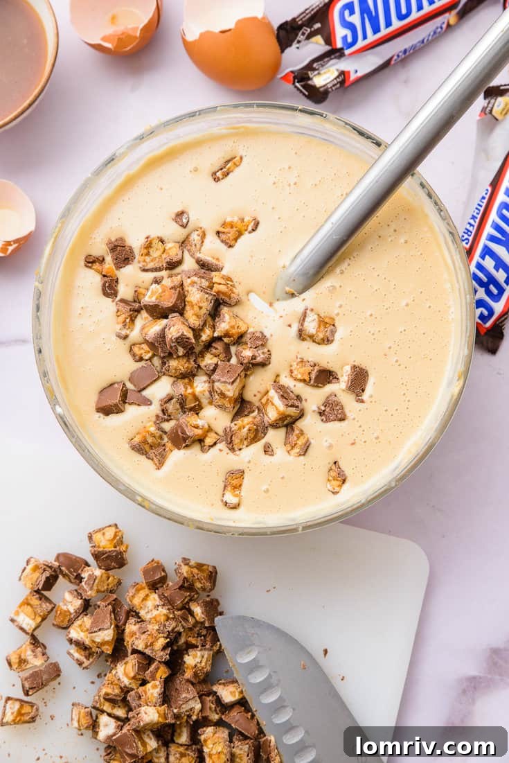 Folding chopped Snickers into peanut butter cheesecake batter