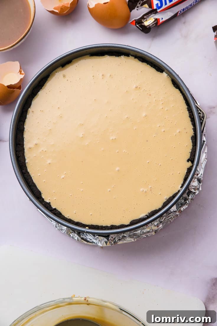 Unbaked Snickers Peanut Butter Cheesecake batter in springform pan