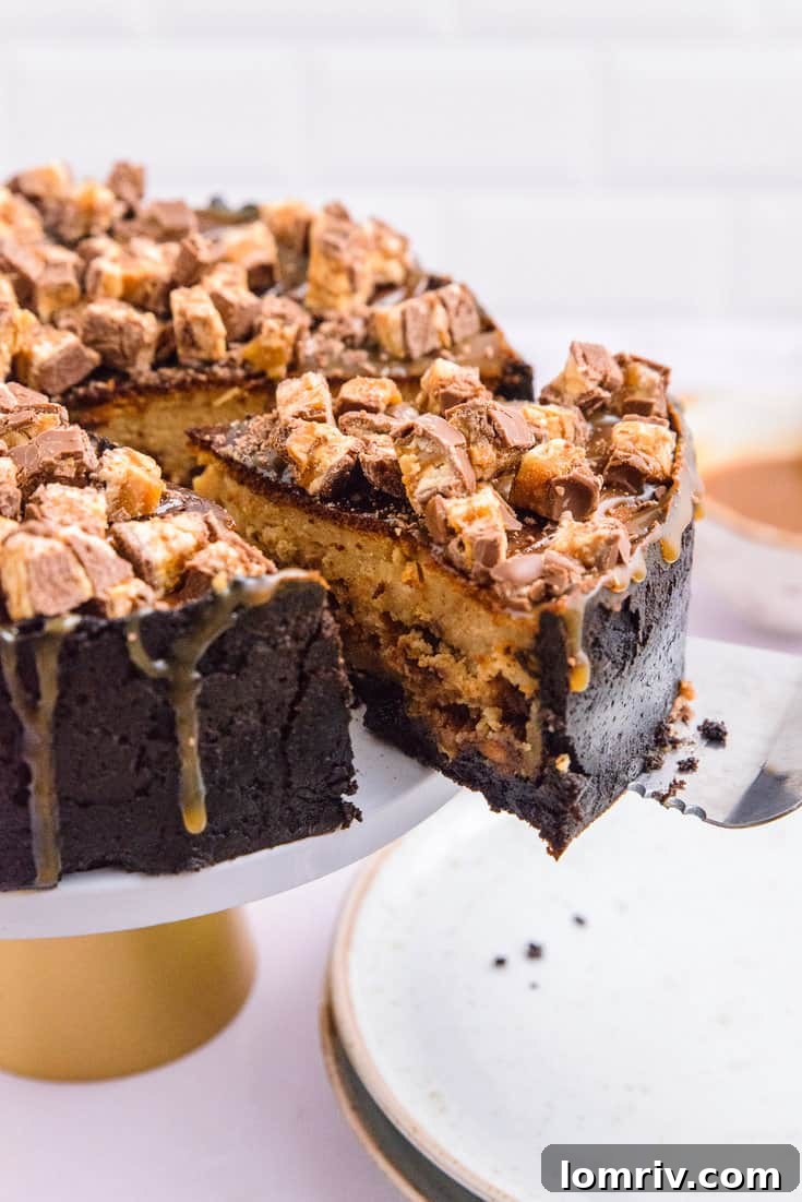Close-up of a slice of Snickers Peanut Butter Cheesecake, showing the layers