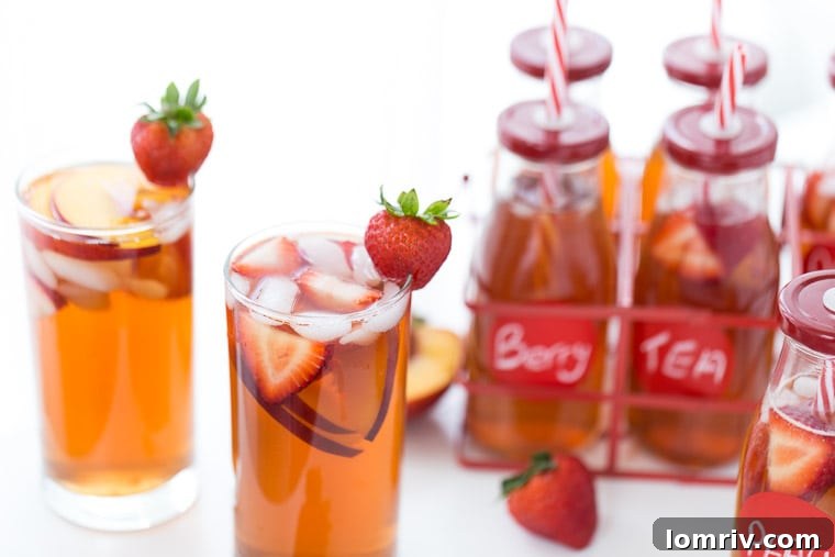 Glass of Strawberry Peach Iced Tea with ice and fresh fruit on a rustic surface