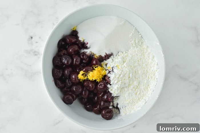 Pitted cherries being tossed with sugar, cornstarch, lemon, vanilla, and bourbon for pie filling