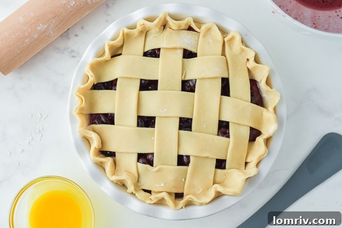 Lattice top being placed on a cherry pie before baking