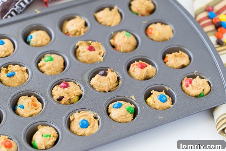 Close-up of a single Pumpkin Spice Donut Hole, showcasing its fluffy texture and M&M's.