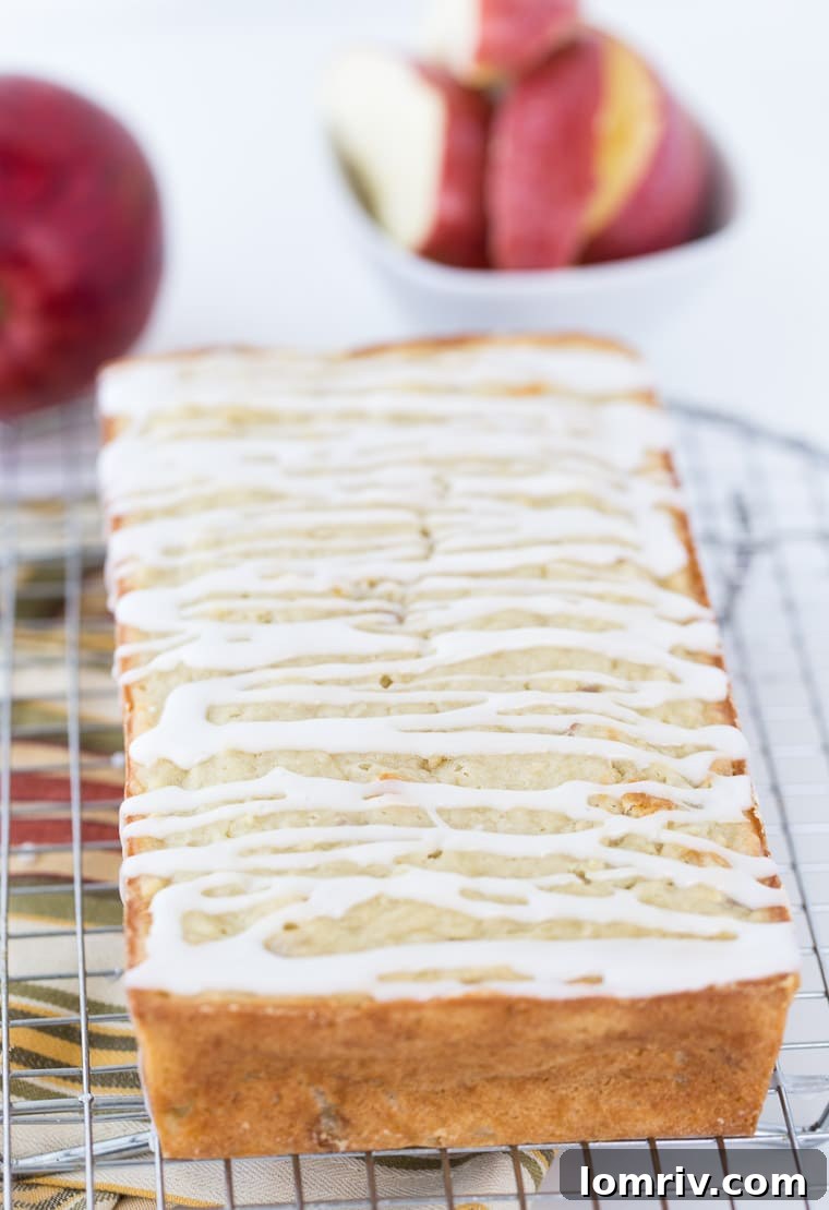 Three loaves of Apple Coconut Bread cooling on a wire rack, drizzled with a simple coconut glaze and sprinkled with flakes.