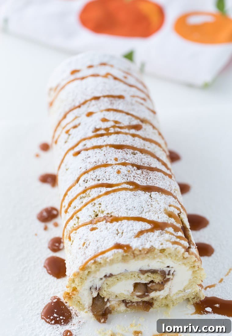 Apple Pie Cake Roll adorned with confectioners' sugar and caramel drizzle