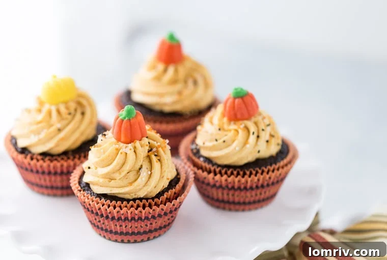 Close-up of frosted chocolate pumpkin cupcakes on a rustic surface.