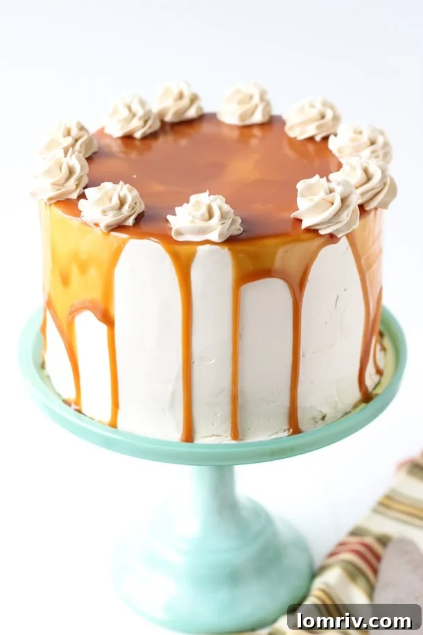 A slice of Spiced Apple Cake with generous layers of creamy Salted Caramel Frosting, garnished with a sprinkle of cinnamon, showcasing a moist cake texture and rich, inviting colors.
