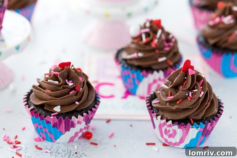 A batch of freshly baked, moist chocolate cupcakes cooling on a wire rack before frosting.